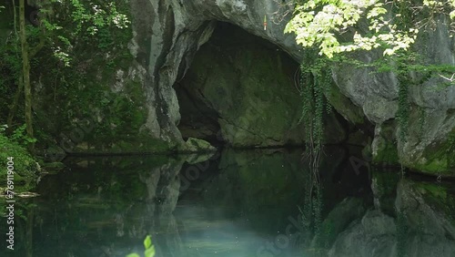 Enchanting video footage of cave entrance above clear lake in woods