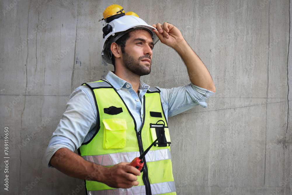 A portrait of a handsome civil engineer or construction engineer wearing a green safety vest at a construction site. A portrait of a handsome civil engineer or construction engineer wearing a green safety vest at a construction site.