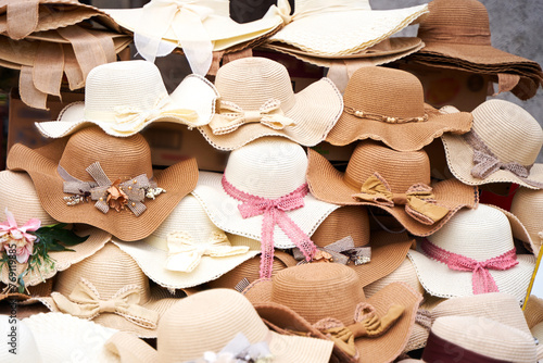 A pile of straw hats is displayed on the street.