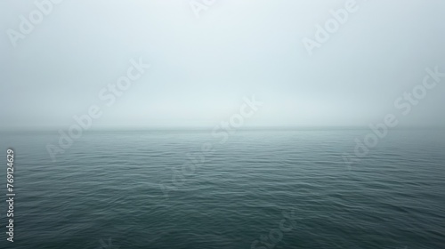   A foggy day, with a solitary boat floating on a vast expanse of water
