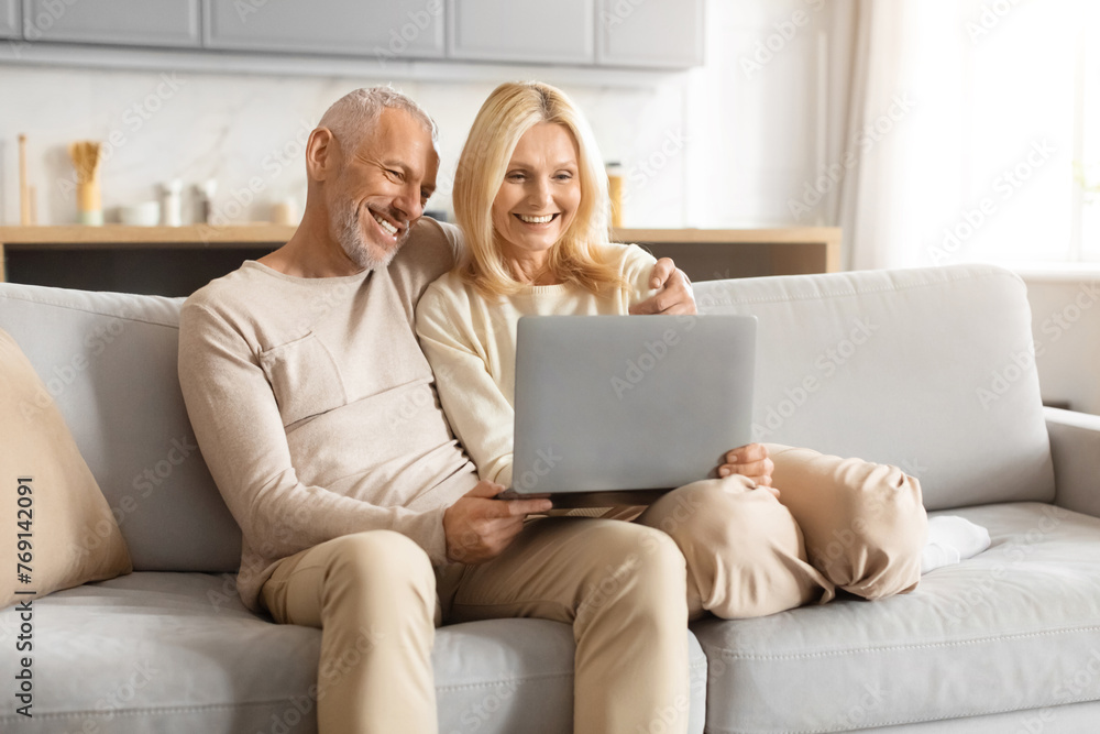 Senior couple laughing while using a laptop Senior couple laughing while using a laptop