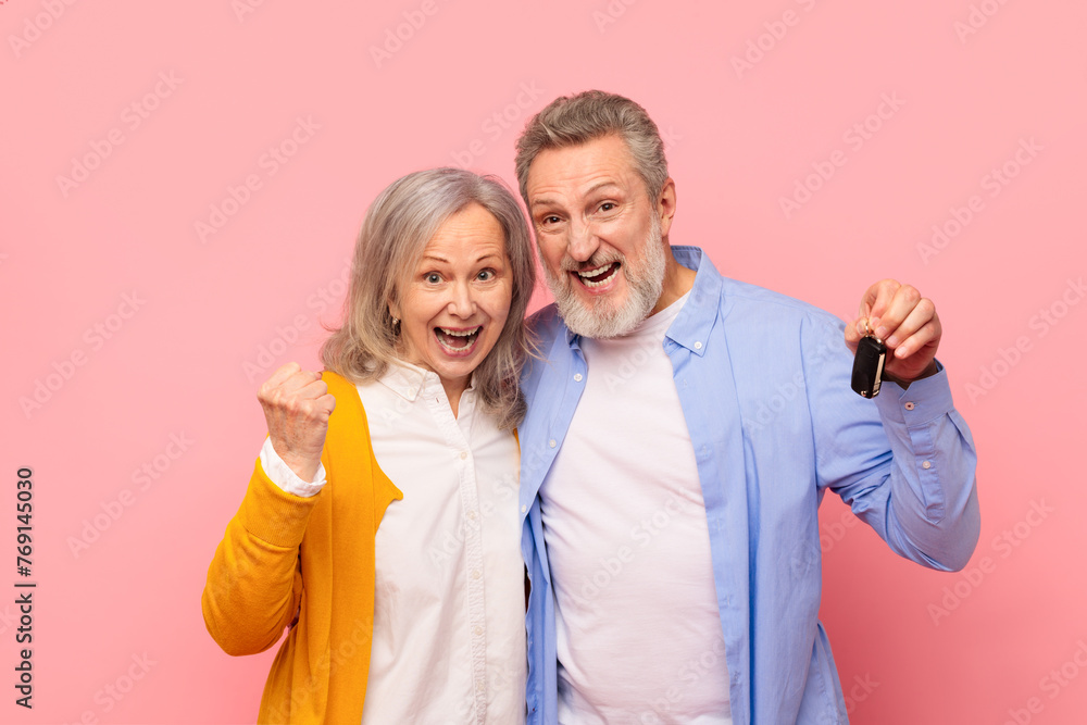 Joyful senior couple holding new car keys gesturing yes, studio Joyful senior couple holding new car keys gesturing yes, studio