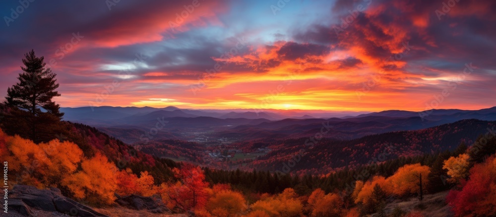 The sun setting over a serene autumn landscape, showcasing the mountains, trees, and colorful foliage
