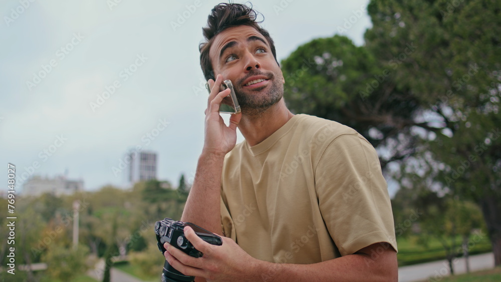 Happy reporter talking smartphone looking photography on camera in park close up Happy reporter talking smartphone looking photography on camera in park close up