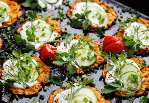 Sweet potato fritters with addition  yogurt sauce, fresh cucumber slices and herbs, focus on the fritter inside, close up view