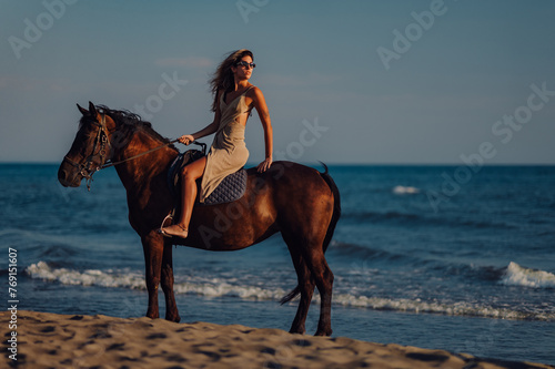 Lady is riding a horse on a beach while looking over her shoulder.