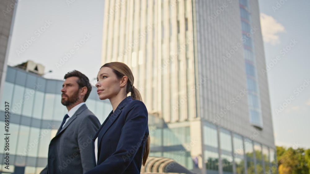 Two businesspeople walking urban district in elegant formal suits close up. Two businesspeople walking urban district in elegant formal suits close up.