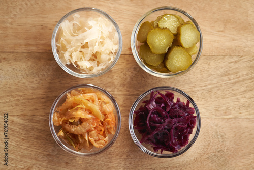 Fermented kimchi, white and purple sauerkraut and gherkins in glass bowls