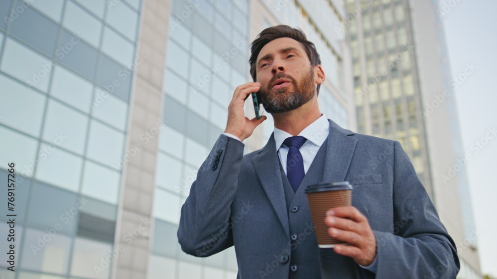 Cheerful manager finish call walking modern street with coffee cup close up. Cheerful manager finish call walking modern street with coffee cup close up.
