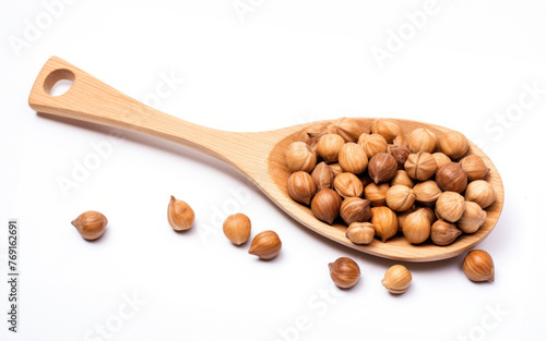Brown hazelnuts on a wooden spoon isolated on white background. Close up view