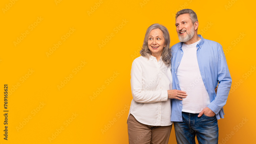 Happy senior couple hugging looking aside at empty space, studio Happy senior couple hugging looking aside at empty space, studio