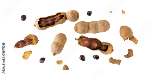 Ripe whole and sopen shelled tamarind fruits with seeds flying isolated on white background.