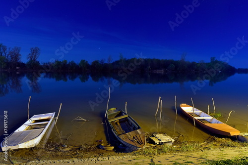 Three lonely boat on the river Tisa at night. photo