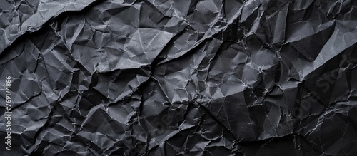 A closeup of a crumpled piece of grey paper on a bedrock, resembling a water pattern, with hints of metal shining through in monochrome photography