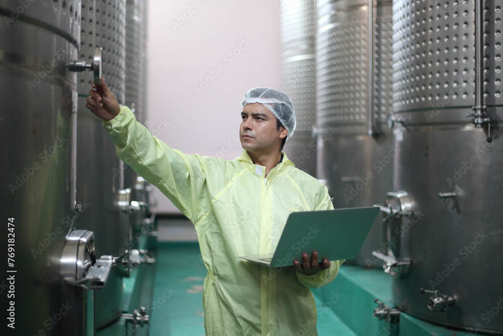 Winemaker working in modern large winery factory drink industry and he testing wine in a wine factory warehouse Winemaker working in modern large winery factory drink industry and he testing wine in a wine factory warehouse