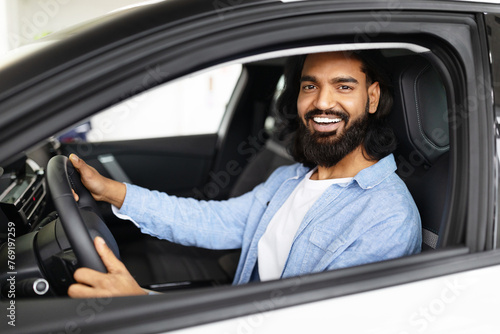 Smiling indian man driving a modern car