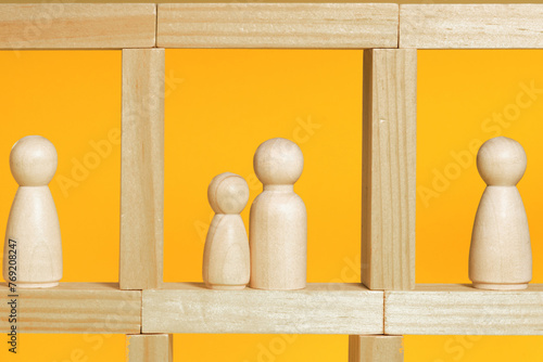 People staying in their flats in apartment house, hospital or prison. Wooden figurines on yellow background