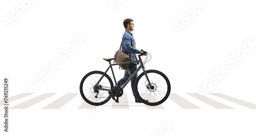 Full length profile shot of a man crossing a street and pushing a bicycle