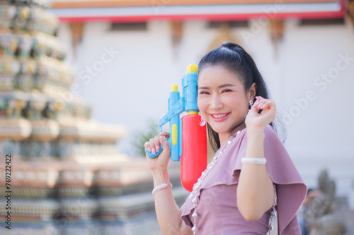 Portrait cheerful young asian woman holding plastic water gun Smiling and having fun playing in the water Songkran festival, Thailand. isolated on pink background. Thai New Year's Day.