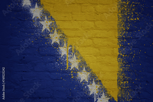colorful painted big national flag of bosnia and herzegovina on a massive brick wall