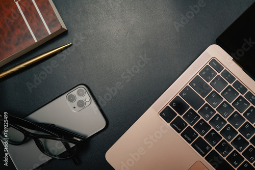Business layout with items for design. Phone, glasses, pen, laptop on the table. In a dark style, there are object layouts on the table. Top view of items
