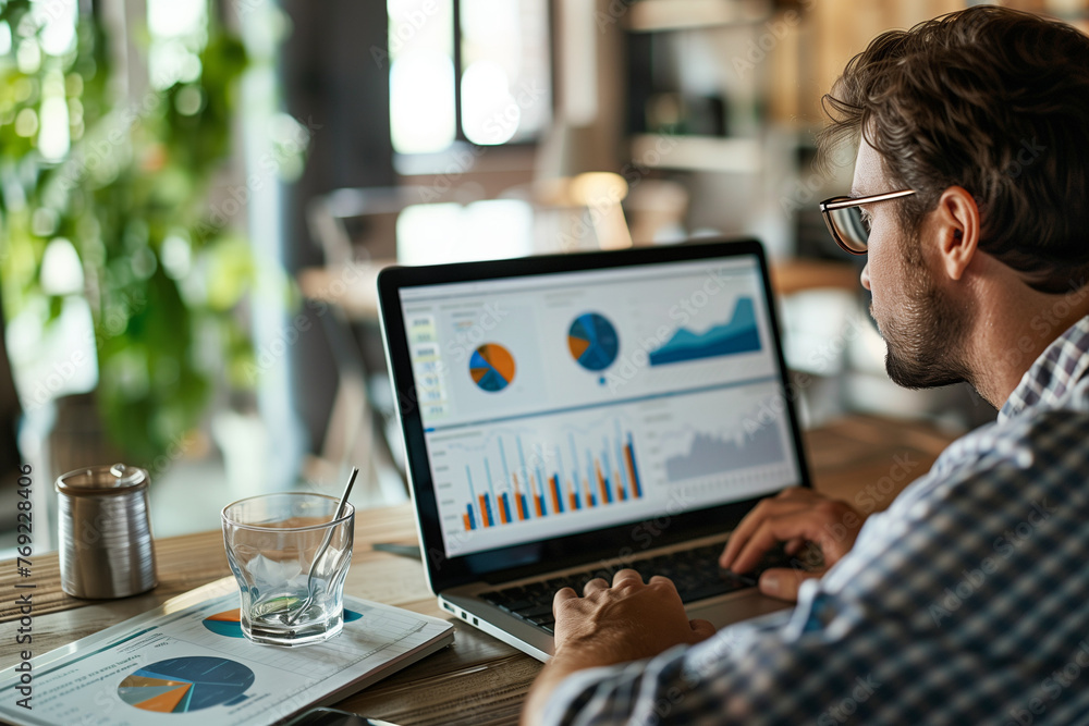A person working on a laptop analyzing financial reports in a casual business setting, which appears to be a modern cafe or co-working space. A person working on a laptop analyzing financial reports in a casual business setting, which appears to be a modern cafe or co-working space.
