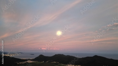 playa con océano iluminada por la Luna, se ve la ciudad a lo lejos, anochecer, Brasil Florianópolis Solidao. (toma aérea). photo