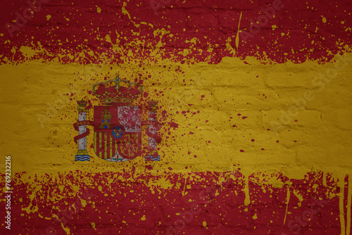 colorful painted big national flag of spain on a massive brick wall