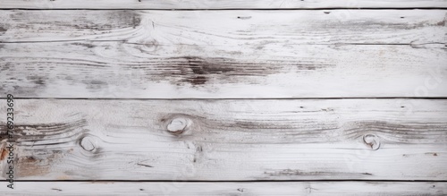 A close up shot of a rectangular white wooden table with a blurred grey background. The hardwood flooring and monochrome photography highlight the intricate wood pattern and metal accents