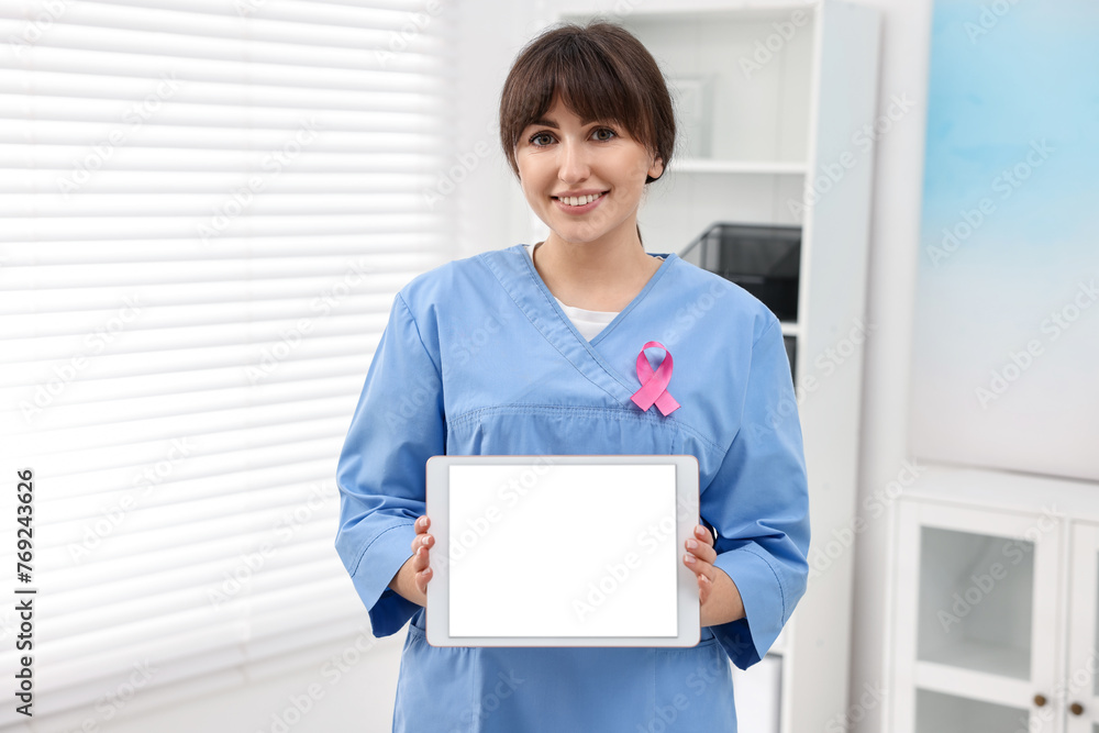 Mammologist with pink ribbon showing tablet in hospital. Breast cancer awareness Mammologist with pink ribbon showing tablet in hospital. Breast cancer awareness