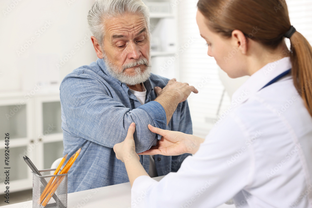 Fototapeta premium Arthritis symptoms. Doctor examining patient's elbow in hospital