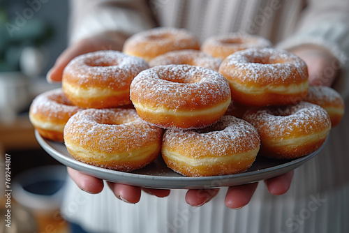 Un montón de donuts frescos sostenidos por un cocinero casero en su cocina.        © Julio