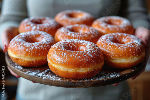 Un mont  n de donuts frescos sostenidos por un cocinero casero en su cocina.       