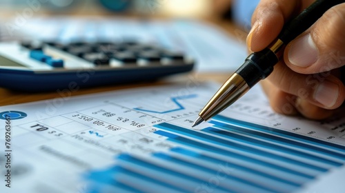Depicts a financial audit in progress,with a person carefully reviewing financial documents and data using a calculator and pen The scene highlights the importance of ensuring photo
