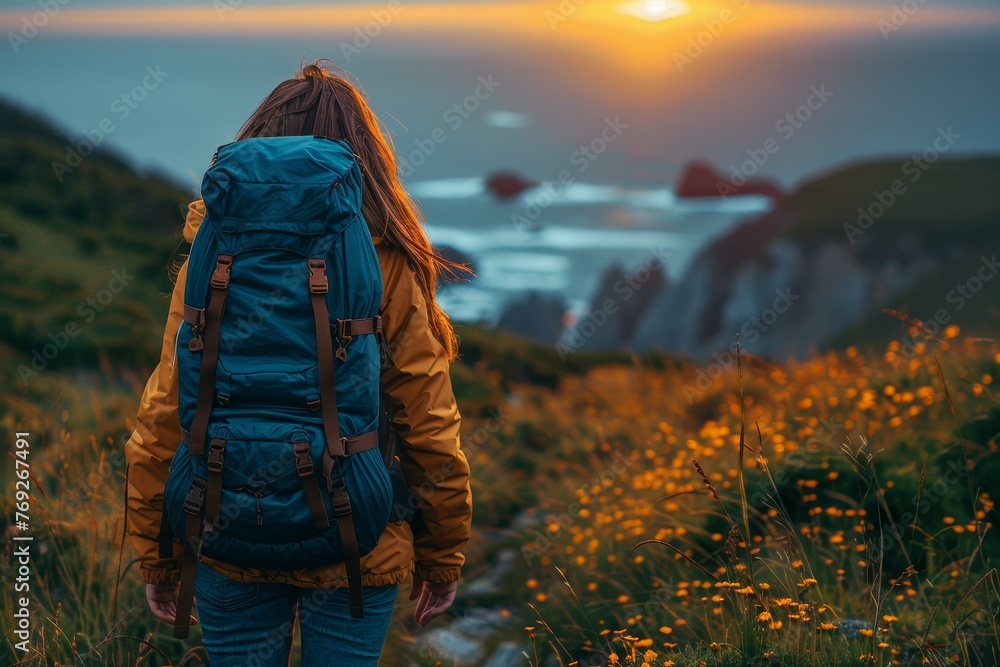 Hiker with backpack admires a picturesque sunset over rolling hills covered with yellow flowers Hiker with backpack admires a picturesque sunset over rolling hills covered with yellow flowers