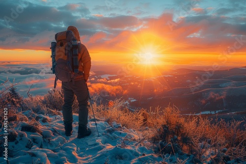 An adventurer braves the cold to witness a breathtaking sunset over snowy mountains and clouds