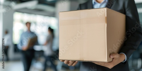 A close-up of a man in a business suit holding a cardboard box.