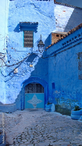 Small, blue, metal door in a blue wall in the medina in Chefchaouen, Morocco © Angela
