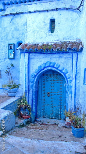 Blue wooden door in a blue wall in the medina in Chefchaouen, Morocco © Angela