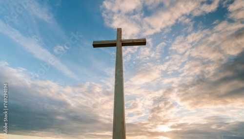 christian cross appears bright in the blue clloudy sky background