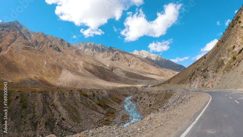 4K shot of beautiful river flowing besides the Himalayan mountains during the sunny day with clouds as seen on the way to Shinkula Pass from Darcha in Lahaul Spiti, Himachal Pradesh, India. photo