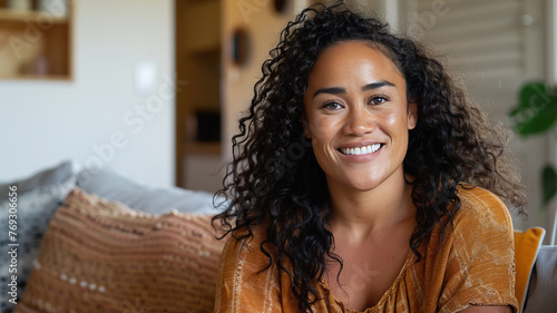 Young Maori woman sitting indoors at home on couch photo