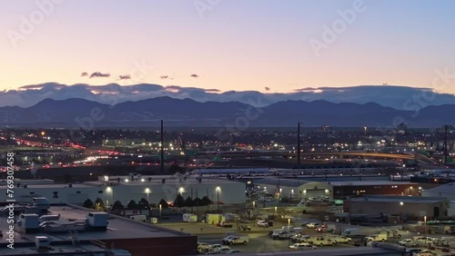 Clouds gather around Rocky Mountainson horizon at dusk as cars commute home passing industrial district photo