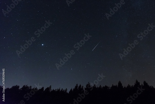 Nachthimmel mit Sternschnuppe und Milchstrasse. Silhouette von Wald. photo