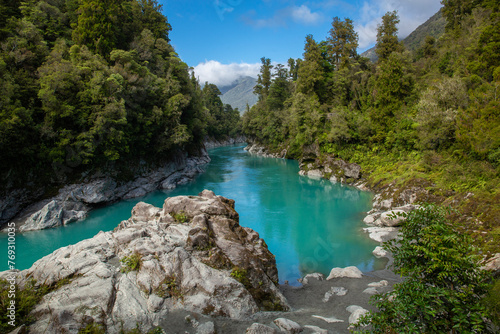 Brilliant turquoise water caused by glacial flour flows through Hokitika Gorge, surrounded by rocky limestone cliffs and lush vegetation on the South Island of New Zealand 