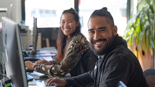 2 people working on a Website in an office setting smiling at the camera, one is MÄori. This image will represent Wordpress Support  photo