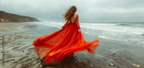 Elegant woman in flowing red dress on beach