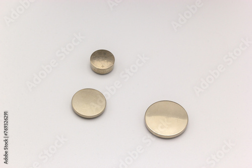 Three circular lithium batteries of different sizes on a white background II (ID: 769326291)