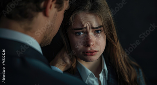 A young woman is crying and the man touches her shoulder to comfort her