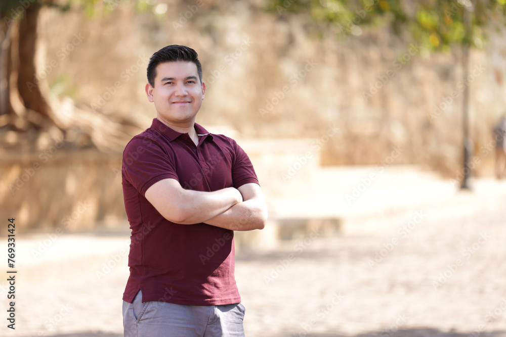 portrait of young mexican man with crossed arms wearing casual wine colored clothes looking at the camera and smiling portrait of young mexican man with crossed arms wearing casual wine colored clothes looking at the camera and smiling